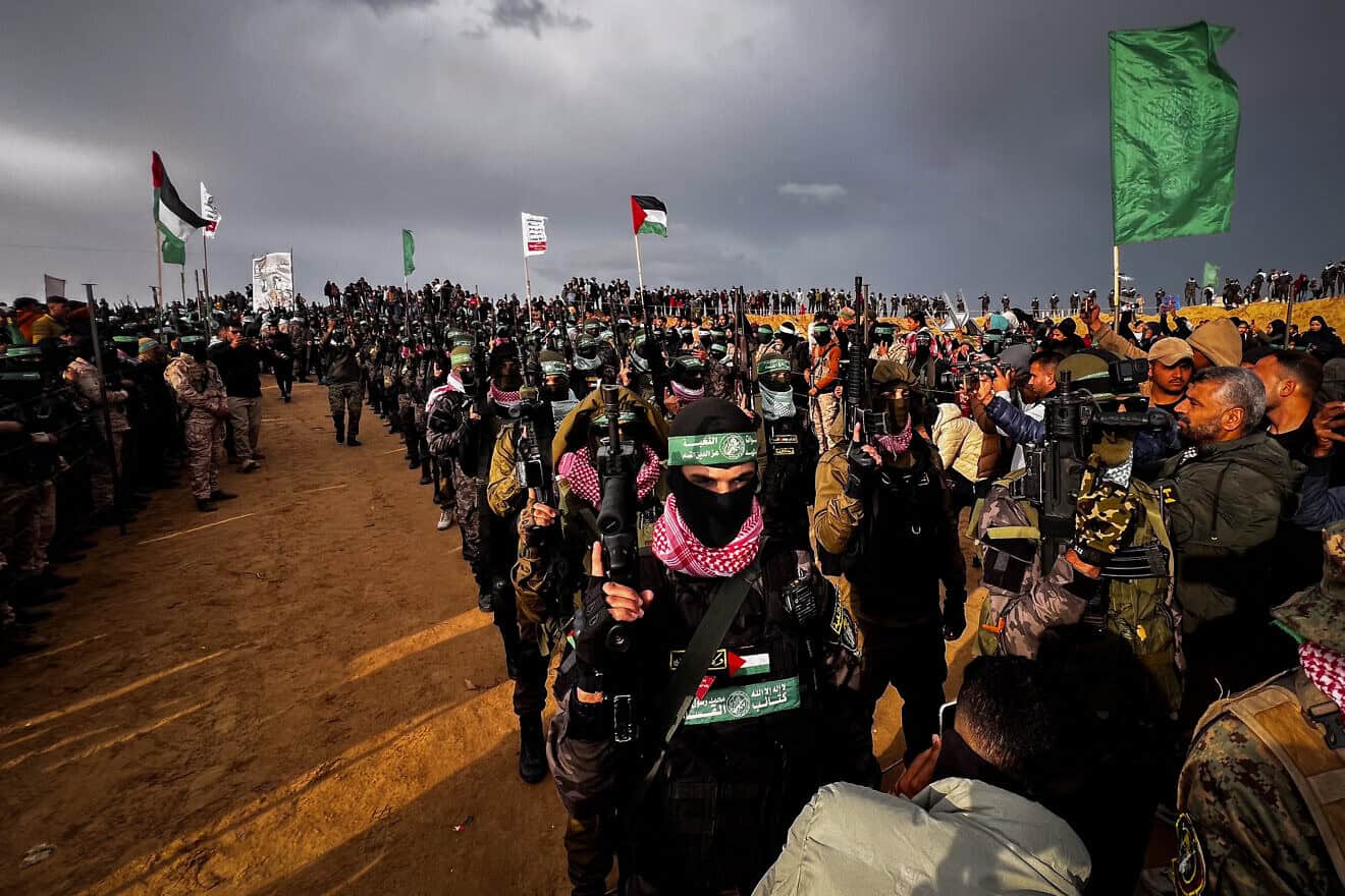 Members of Al-Qassam Brigades, the Hamas 'military" wing, stand guard while Palestinians wait to hand over the bodies of four Israeli hostages to the Red Cross in Khan Yunis, the southern Gaza Strip, Feb. 20, 2025. Photo by Saeed Mohammed/Flash90.