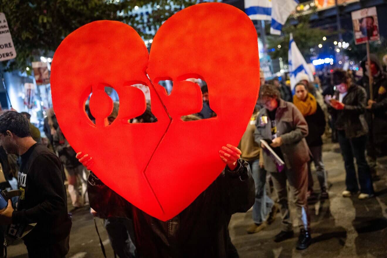 People gather outside of the Kirya base in Tel Aviv on the day that the bodies of four Israeli hostages were released from Hamas captivity, including the youngest two, Ariel and Kfir Bibas (a broken heart shows their last name in Hebrew) and their mother, Shiri Bibas, on Feb. 20, 2025. Photo by Chaim Goldberg/Flash90.