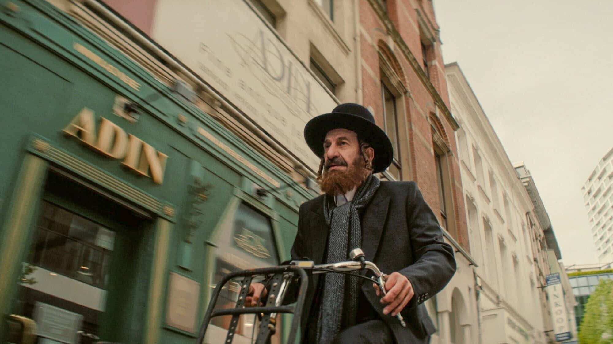 Nuchem Shtisel (played by Sasson Gabay) rides a bicycle through Amsterdam in “Kugel.” Credit: Courtesy of IZZY.