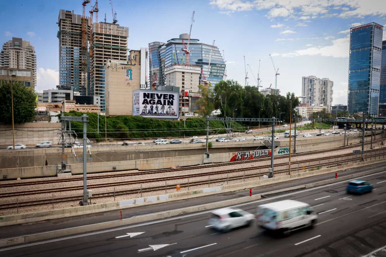 A large billboard with the words “Never Again” above the Ayalon highway in Tel Aviv, Oct. 18, 2023. Photo by Chaim Goldberg/Flash90.