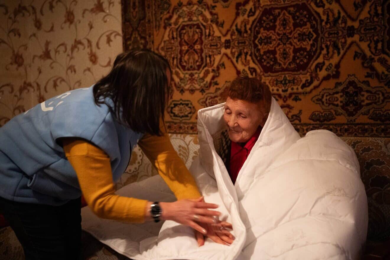 A homecare worker from the American Jewish Joint Distribution Committee (JDC) delivers a life-saving warm blanket and provides essential companionship to an elderly client on a cold winter day in Sumy, Ukraine. Photo by Arik Shraga.