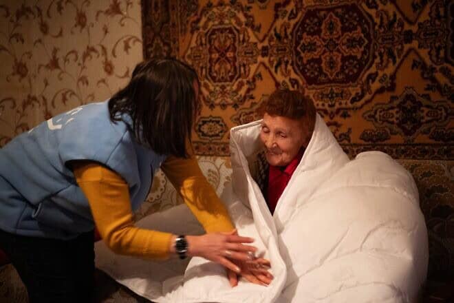 A homecare worker from the American Jewish Joint Distribution Committee (JDC) delivers a life-saving warm blanket and provides essential companionship to an elderly client on a cold winter day in Sumy, Ukraine. Photo by Arik Shraga.