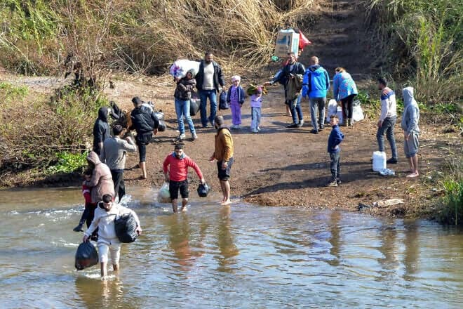 Alawites cross the Nahr al-Kabir river, forming the border between Syria's western coastal province and northern Lebanon in the Hekr al-Daher area, fleeing sectarian violence in their heartland along Syria's Mediterranean coast, on March 11, 2025. Photo by Fathi al-Masri/AFP via Getty Images.