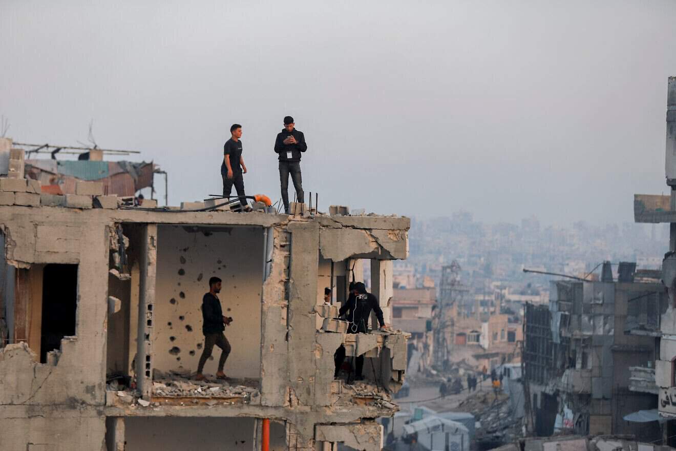Men stand on a damaged rooftop overlooking an Iftar break-fast gathering in Beit Lahia, northern Gaza, on March 15, 2025. Photo by Saeed Jaras/Middle East Images/AFP via Getty Images.