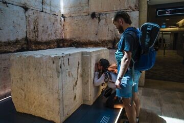 Shelly Sarah, a 22 year old Israeli from Hadera, stops at the Western Wall stone on display at Israel's Ben-Gurion International airport before a trip to Thailand as her boyfriend looks on, March 25, 2025. Credit: Rina Castelnuovo.
