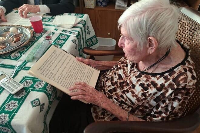 A JBI Library patron reads from a large print haggadah at her family Passover seder. Credit: Courtesy of JBI Library.
