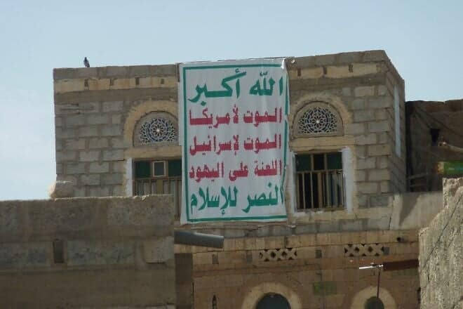 A banner with the "Sarkha," translated as "God is the Greatest, Death to America, Death to Israel, Curse be upon the Jews, Victory to Islam," the political slogan of the Houthis, on a house in Dhamar, Yemen, Sept. 26, 2013. Credit: Abdullah Sarhan via Wikimedia Commons.