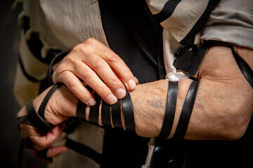Holocaust survivor Moshe David Meir, 92, with tefillin and number that was tattooed on his arm at a Nazi concentration camp, at his home in Jerusalem. Meir survived the Birkenau concentration camp during the Holocaust. June 21, 2023. Credit: Chaim Goldberg/Flash90.