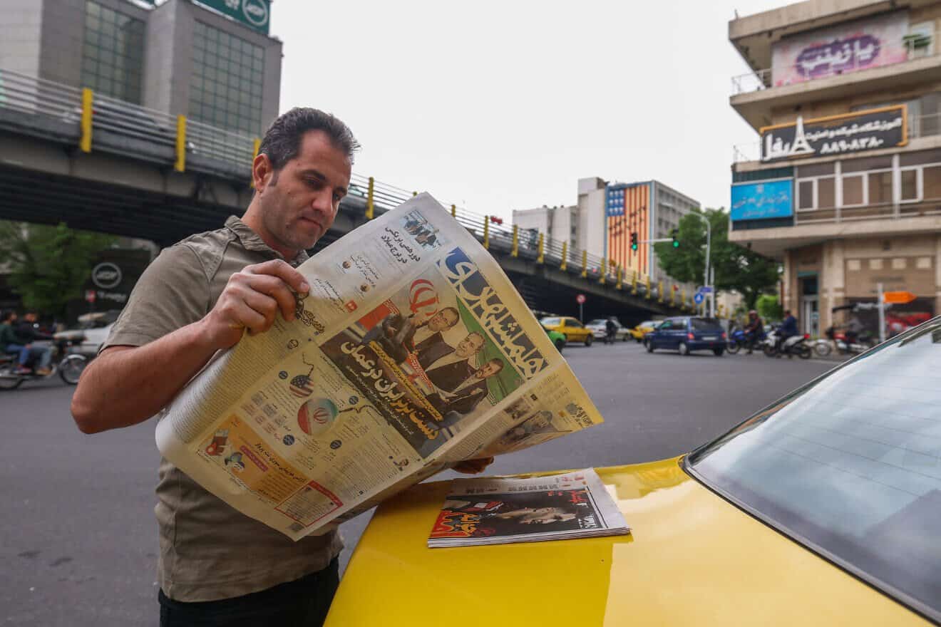 A man reads a newspaper in Tehran, with the front page featuring the Iran-U.S. talks on the Iranian nuclear program set to begin in Oman on the same day, April 12, 2025. Photo by Atta Kenare/AFP via Getty Images.