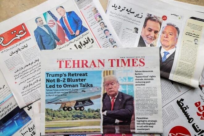 A picture shows front-page newspaper headlines at a kiosk in Tehran, featuring Iran-U.S. talks on the Iranian nuclear program to begin in Oman, April 12, 2025. Photo by Atta Kenare/AFP via Getty Images.